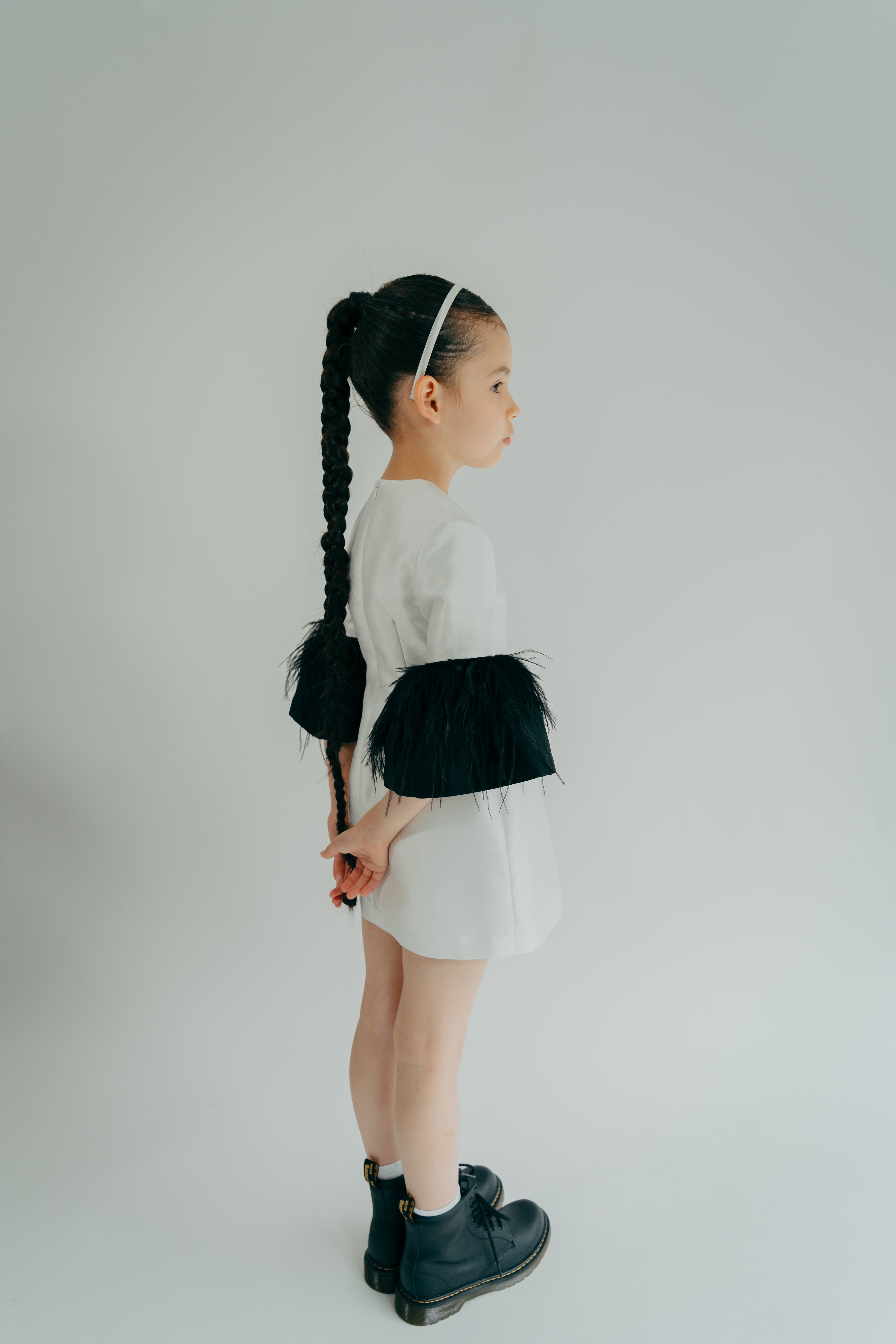 Girl quietly posing in a white simple dress with puffy black sleeves