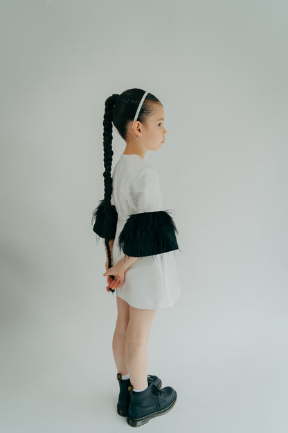 Girl quietly posing in a white simple dress with puffy black sleeves