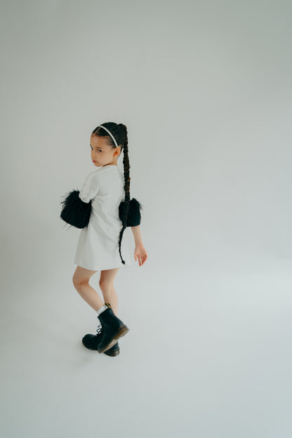 Youn girl wearing a cute white dress with balck feather mid-sleeves